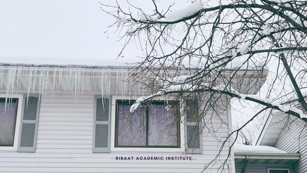 Image of a white building in the winter time, frozen icicles draping down the front of the building and the words Ribaat Academic Institute are written in the color purple
